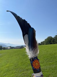 Midsection of woman with umbrella on field against sky