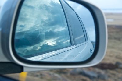 Reflection of clouds in side-view mirror