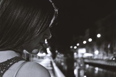 Rear view of woman by illuminated canal