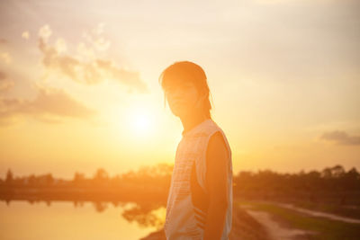 Portrait of woman standing against sea and sky during sunset