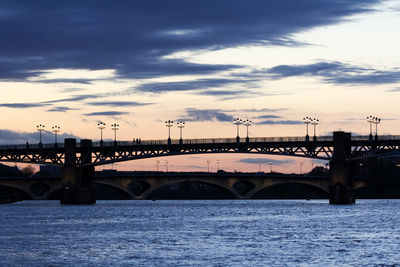 Bridge over river against sky during sunset