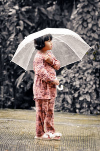 Boy holding umbrella standing during rainy season