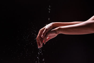 Close-up of person splashing water against black background
