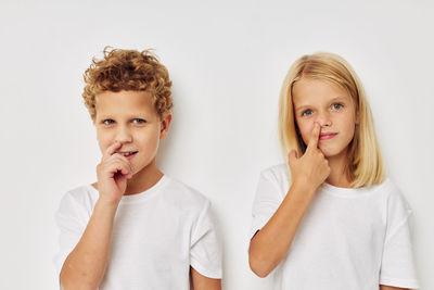 Portrait of boy and girl standing against white background