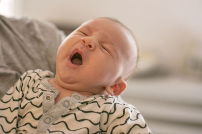 Close-up of mother carrying sleeping baby boy at home