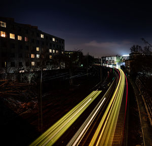 High angle view of light trails on street amidst buildings at night