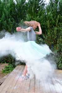 Girl dancing amidst dust on floorboard in back yard