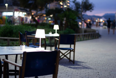 Empty chairs and tables at sidewalk cafe