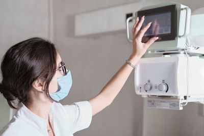 Hospital radiology. beautiful multiethnic woman adjusting x-ray machine in modern clinic