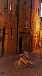 Man riding bicycle on street against buildings in city