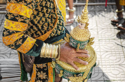 Midsection of woman holding golden statue in temple