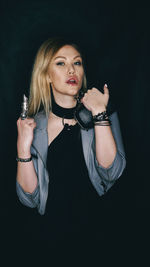 Portrait of young woman against black background