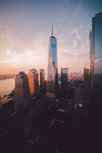 Modern buildings in city against sky during sunset