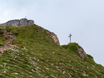 Low angle view of cross on rock against sky