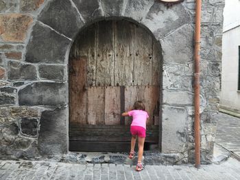 Rear view of woman standing by building