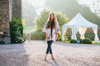 Full length portrait of woman standing against wall