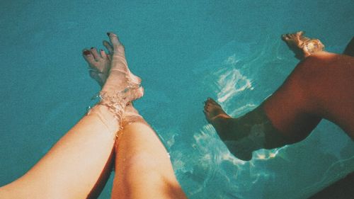 Low section of couple relaxing in swimming pool