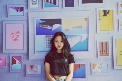 Portrait of teenage girl standing against frames