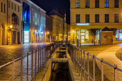 Illuminated bridge over canal amidst buildings at night