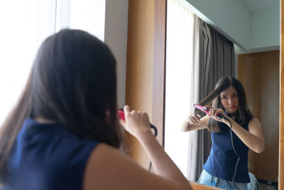 Woman straightening hair at home