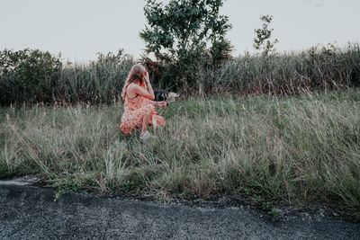 Woman with umbrella on field against sky