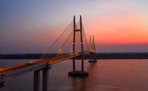 Sailboat on bridge over sea against sky during sunset