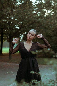 Portrait of woman with arms raised standing in park