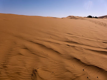 Sand dunes in desert against clear sky