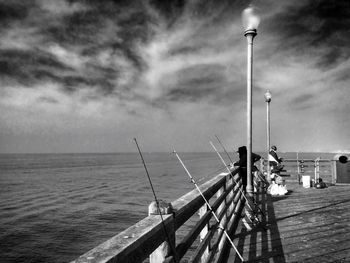 Pier on sea against cloudy sky