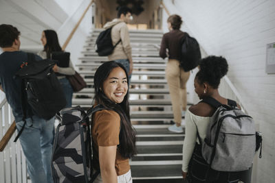 Portrait of happy female student with multiracial friends at university