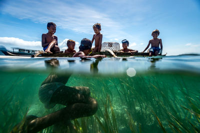 People swimming in pool against sea
