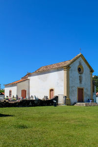 Built structure on field against clear blue sky