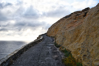 Scenic view of sea by mountain against sky