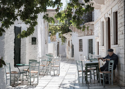 Man sitting on table at sidewalk cafe amidst buildings