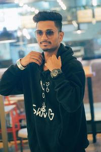 Young man wearing sunglasses standing in restaurant