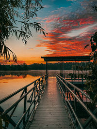 Footbridge over lake against sky during sunrise 