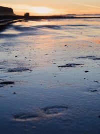 Surface level of beach against sky during sunset