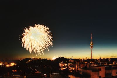 Low angle view of firework display over city at night