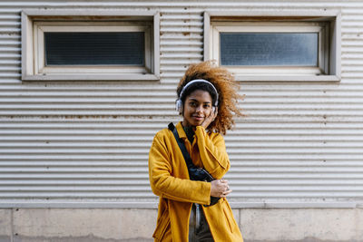 Portrait of woman standing against wall in city