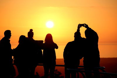 Silhouette of people photographing sunset