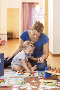 Mother and baby boy playing toys on floor at home