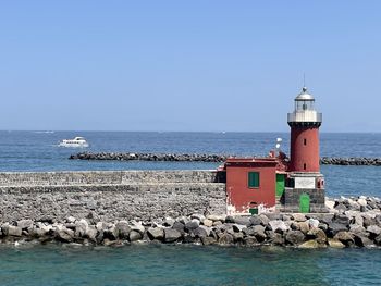 Lighthouse by sea against sky