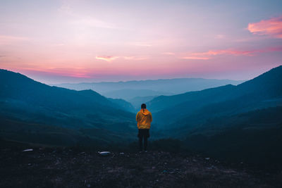 Rear view of man standing on mountain against sky