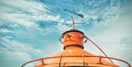 Low angle view of weather vane against sky