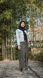 Woman standing against bamboo grove in forest