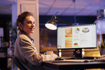 Portrait of young woman using mobile phone in office