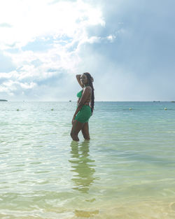 Beautiful caribbean female with locs in a green swimsuit at the beach