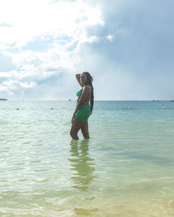 Rear view of woman standing in sea against sky