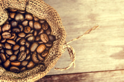 High angle view of roasted coffee beans in sack on wooden table
