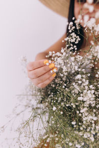 Woman with yellow nails touching baby breath flowers